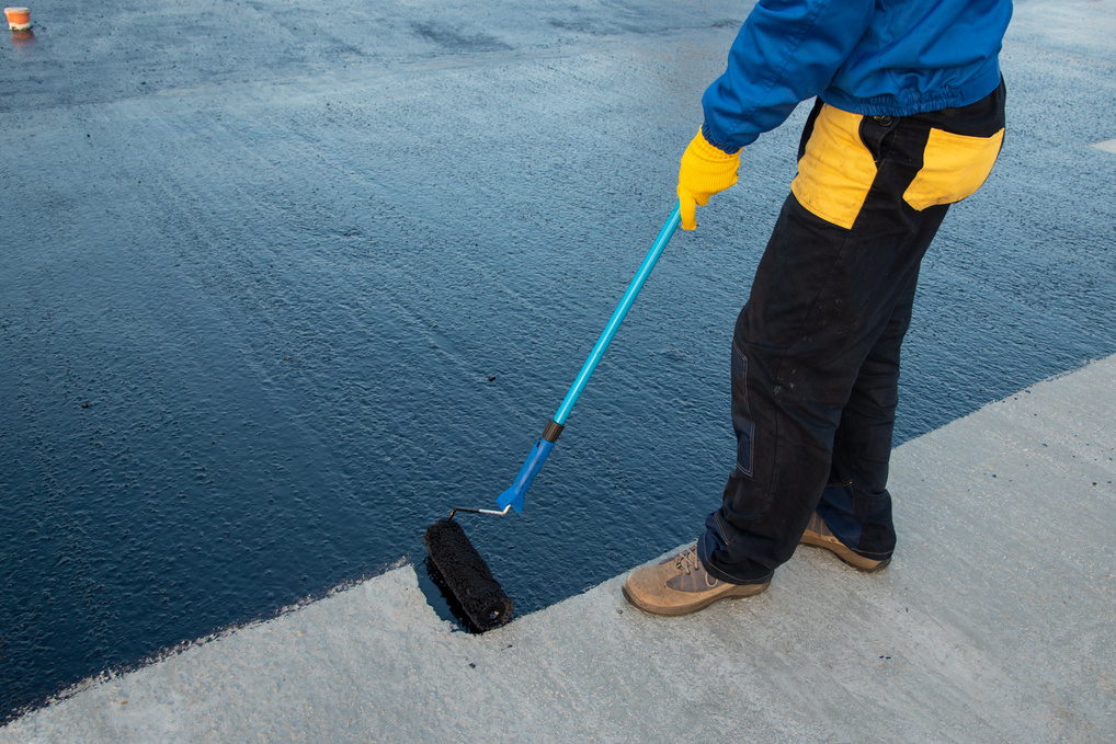 Worker applies bitumen mastic on the foundation